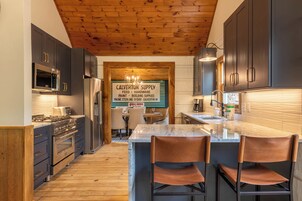 Una cocina moderna con armarios oscuros, electrodomésticos de acero inoxidable y techo de madera.