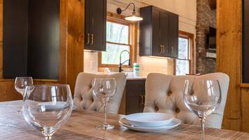 A dining table with four wine glasses and plates, a wooden table, and dark wooden cabinets in a cozy kitchen setting.