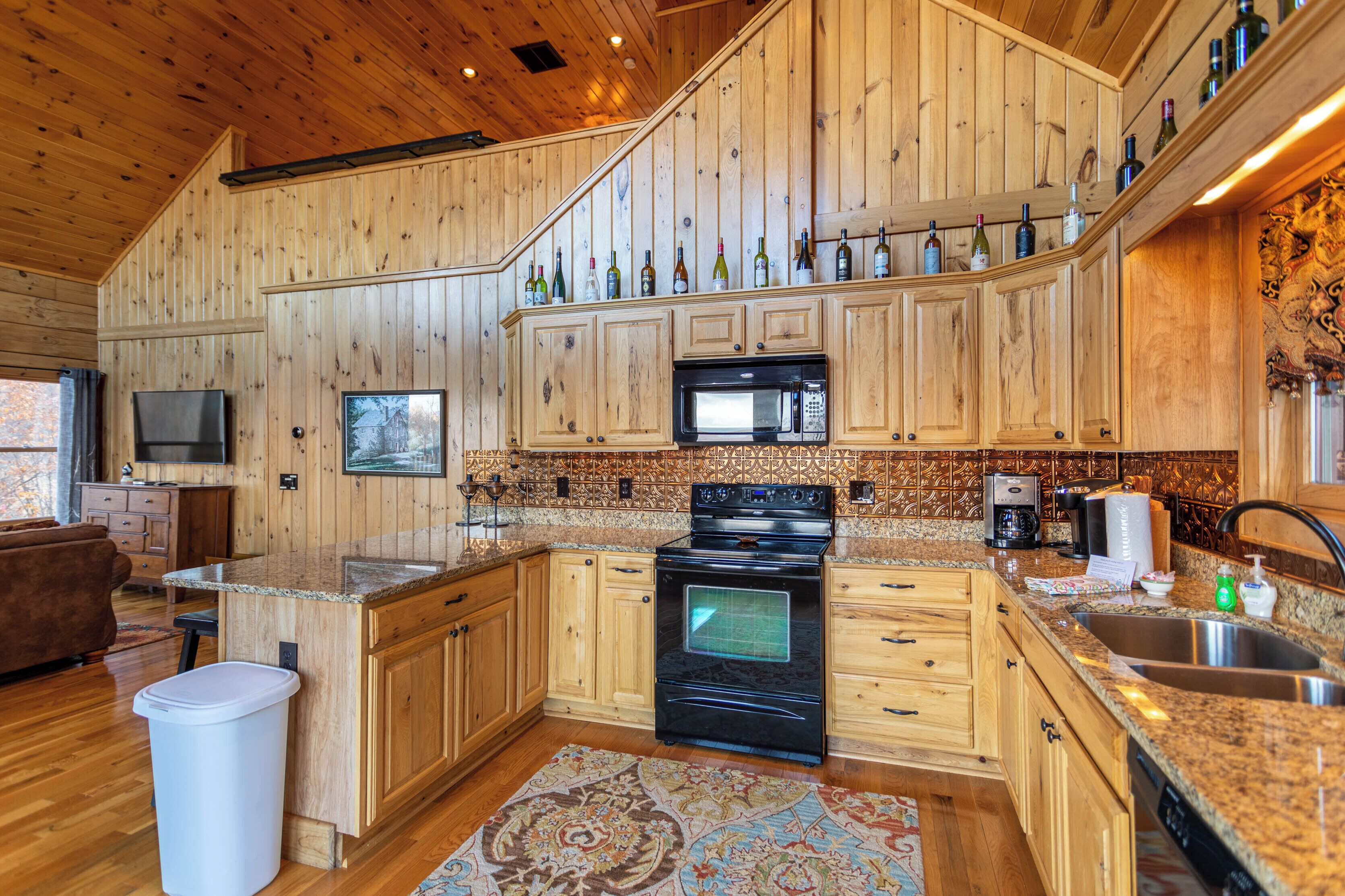 A kitchen with wooden cabinets, a microwave, a stove, and a countertop with bottles.