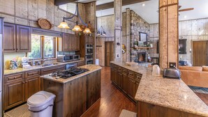 A spacious kitchen with granite countertops, wooden cabinets, and a large island. - Hawk Haven (Banner Elk)