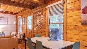 Un interior de madera con una mesa de comedor, sillas, un sofá y una brújula en la pared.