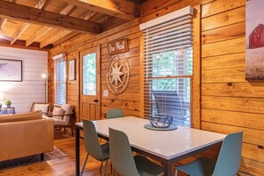 Ein Holzinterieur mit Esstisch, Stühlen, einer Couch und einem an der Wand befestigten Kompass.