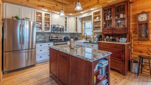 A kitchen with wooden cabinets, stainless steel appliances, granite countertops, and pendant lighting.