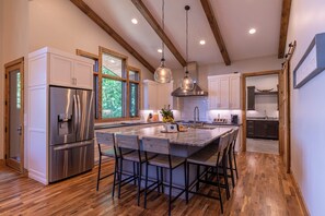 A modern kitchen with a central island, stainless steel appliances, and wooden beams on the ceiling. - The Recovery Room at Eagles Nest (Banner Elk)