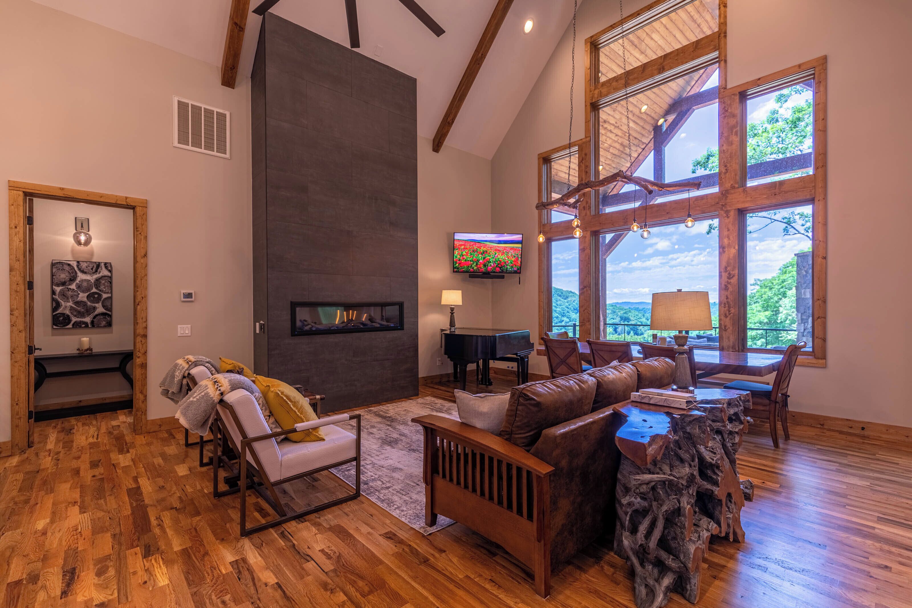 Amplia sala de estar con chimenea, un piano y un ventanal con vistas al exterior.