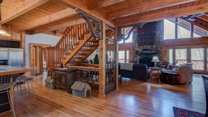 A spacious wooden interior with a staircase, a stone fireplace, and a dining area. - Boles Lodge (Boone)