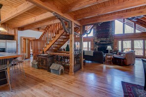 Ein geräumiger Holzinnenraum mit Treppe, Kamin aus Stein und Essbereich.
