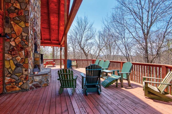 Eine Holzterrasse mit Adirondack-Stühlen, einer Steinmauer und einem roten Geländer.