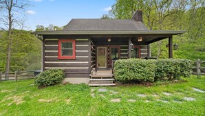 A log cabin with a porch, steps leading to the door, and a small garden area. - Valle Creek Cabin (Vilas)