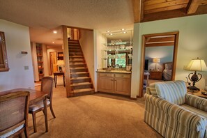 Ein Innenraum mit Treppe, Essbereich, Küche mit Glaswaren und Wohnzimmer mit Sofa.