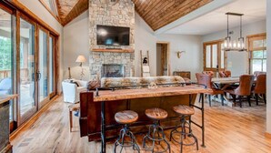 A rustic interior with a stone fireplace, wooden ceiling, and a bar area with stools. - High Country Hideaway at Eagles Nest (Banner Elk)