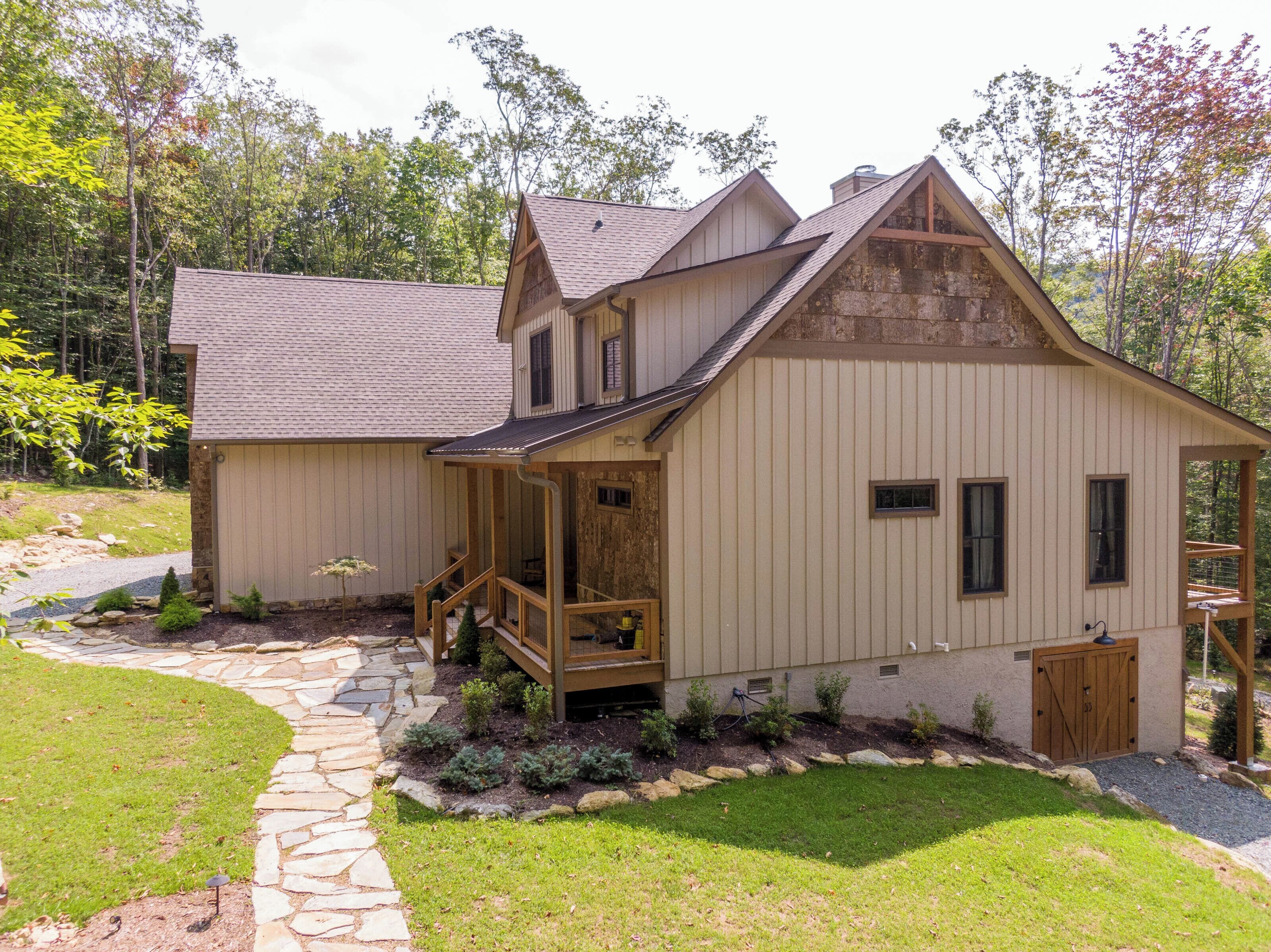 A two-story house with a stone pathway leading to the front door, a wooden porch, and a small garden area.