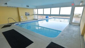 Ein Hallenbad mit einem Sprungverbotsschild, einer Leiter und Blick ins Freie.