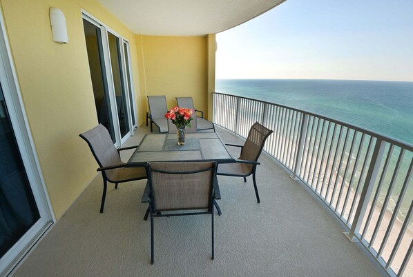 A balcony with a table, chairs, and a vase of flowers.