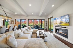 A spacious living room with a sectional sofa, a fireplace, and a large TV mounted on the wall. - Maynard Rocks IV at Elk Creek (Banner Elk)