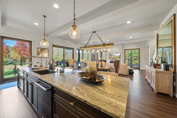 A spacious kitchen with a large island, pendant lighting, and large windows offering views of the outdoors. - Maynard Rocks IV at Elk Creek (Banner Elk)