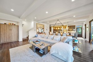 A spacious living room with a large sectional sofa, a coffee table, and a dining area with a chandelier. - Maynard Rocks IV at Elk Creek (Banner Elk)
