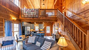 Ein geräumiges Holzhaus-Interieur mit Essbereich, Küche und einer Treppe, die zu einer oberen Ebene führt.