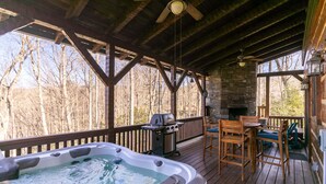 Eine Holzterrasse mit Whirlpool, Grill und Tisch mit Stühlen.