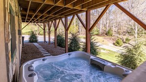 A hot tub under a wooden structure with a view of a forested area. - Rhododendron Rendezvous (Blowing Rock)