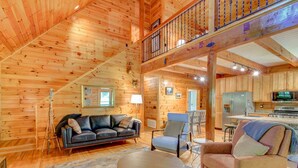 A wooden interior with a sofa, chairs, a dining table, and a kitchen area. - Rhododendron Rendezvous (Blowing Rock)