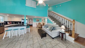 A spacious living area with a kitchen, a staircase, and a dining area. - Sundancers (Galveston)
