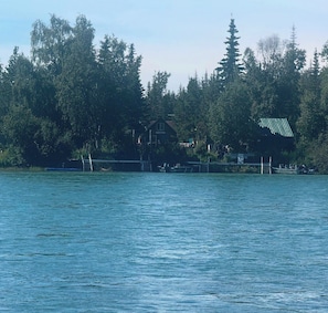 Ein Haus am See mit einem Steg, umgeben von Bäumen.