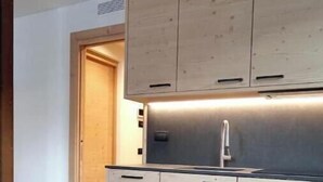 A modern kitchen with wooden cabinets, a stainless steel sink, and a dark countertop. - 3 - Bormio Apartments Al Pradais - First P. WEST (Bormio)