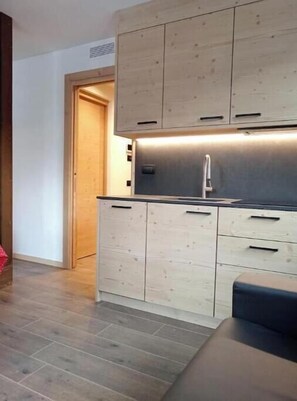 Eine moderne Küche mit Holzschränken, einer Edelstahlspüle und einer dunklen Arbeitsplatte.