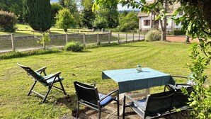 A patio with a table and chairs, surrounded by a fence and greenery.