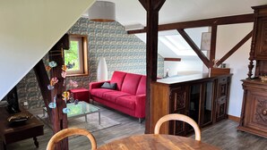A room with a red sofa, wooden dining table, and a glass coffee table.