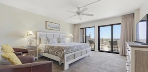 Ein Schlafzimmer mit Bett, Schreibtisch, Stuhl, Fernseher und einem Balkon mit Blick.