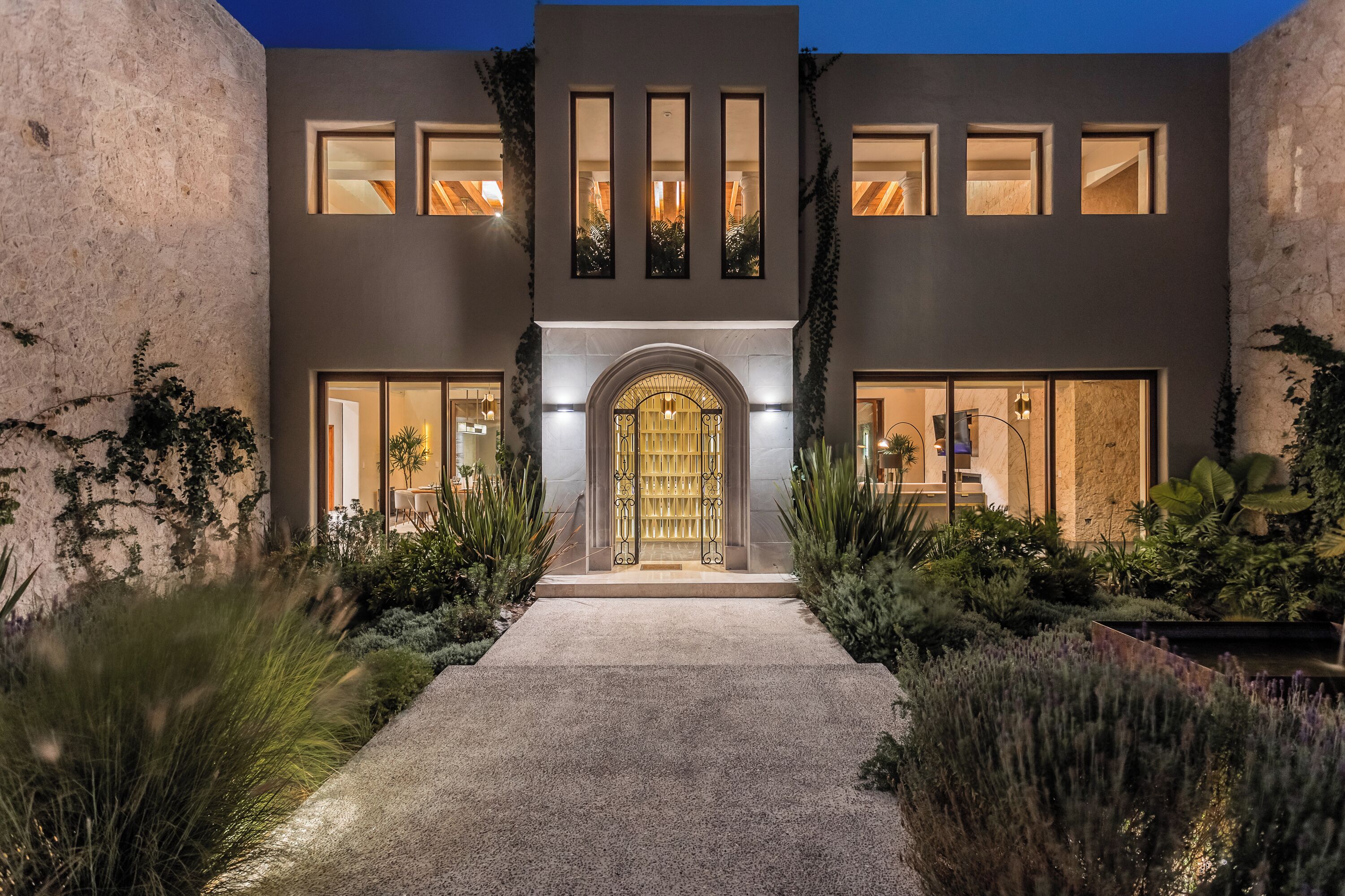 A modern two-story building with a central entrance, large windows, and a well-maintained garden.
