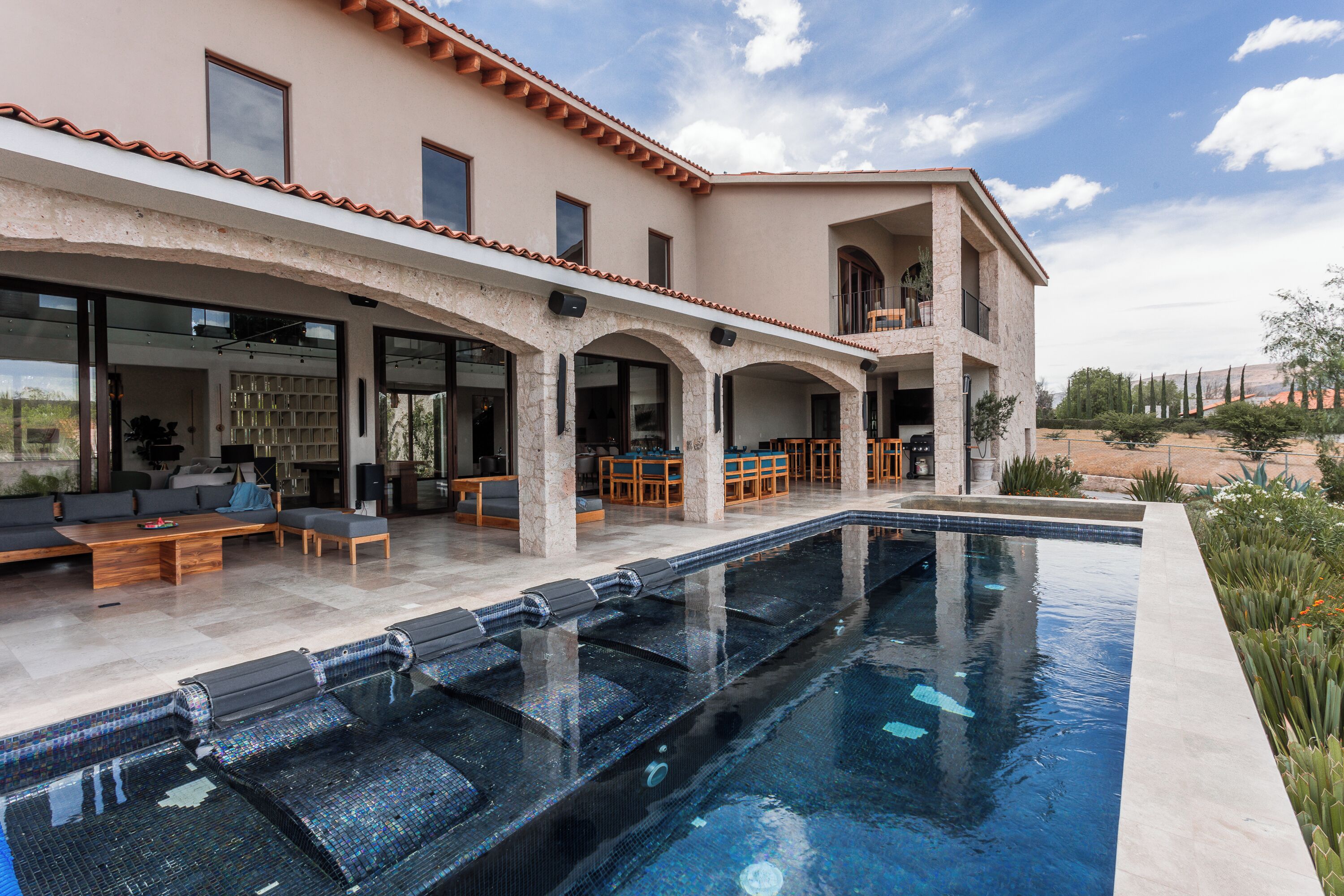 A modern house with a swimming pool, outdoor seating, and a view of the landscape.