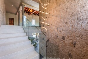 Eine Treppe mit Glasgeländer, einer Steinsäule und einer Holztür.