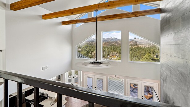 A high-ceilinged room with exposed wooden beams, large windows offering mountain views, and a modern pendant light. - Modern Mountain Retreat in beautiful Ruidoso (Ruidoso)