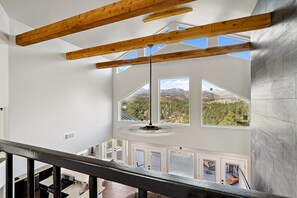 A high-ceilinged room with exposed wooden beams, large windows offering mountain views, and a modern pendant light. - Modern Mountain Retreat in beautiful Ruidoso (Ruidoso)