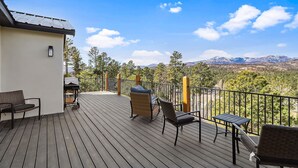 A wooden deck with outdoor furniture, a barbecue grill, and a view of mountains and trees. - Modern Mountain Retreat in beautiful Ruidoso (Ruidoso)