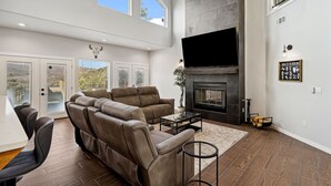 A spacious living room with a sectional sofa, a fireplace, and a large TV. - Modern Mountain Retreat in beautiful Ruidoso (Ruidoso)