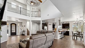 A spacious living area with a large sectional sofa, a dining table, and a kitchen in the background. - Modern Mountain Retreat in beautiful Ruidoso (Ruidoso)