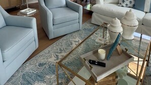 Sala de estar com um lustre, dois sofás, uma mesa de centro e uma escada.