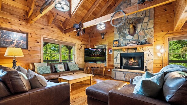Ein Holzblockhaus-Interieur mit Kamin, Holzmöbeln und einer Steinwand.