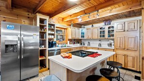 Eine moderne Küche mit Holzausbau, einem Edelstahlkühlschrank und einer zentralen Kochinsel mit Hockern.