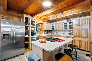 Eine moderne Küche mit Holzausbau, einem Edelstahlkühlschrank und einer zentralen Kochinsel mit Hockern.