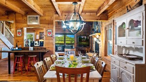 Ein Holzinterieur mit einem für sechs Personen gedeckten Esstisch, einer Bar und einer Küche mit weißen Schränken.