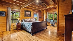 Ein Schlafzimmer einer Holzhütte mit einem Bett, einem Schreibtisch und einem Stuhl.