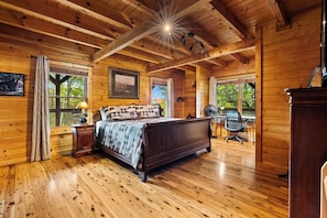 Ein Schlafzimmer einer Holzhütte mit einem Bett, einem Schreibtisch und einem Stuhl.