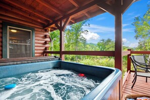 Ein Whirlpool auf einer Holzterrasse mit Blick auf eine bewaldete Landschaft.
