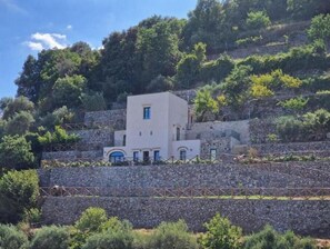 A white building with a small balcony, surrounded by stone walls and greenery. - The little tower of Minuta - Allegro con Brio - retreat on the Amalfi Coast (Scala Costiera amalfitana)