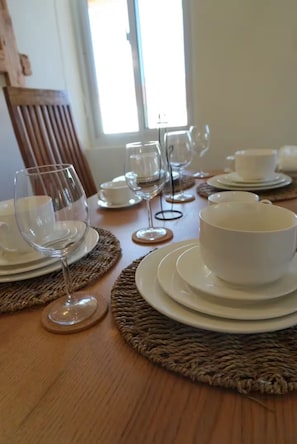 A dining table set with white plates, bowls, and wine glasses, arranged on woven placemats. - The Sunny Villa Near Ritz Carlton&Palm Beach (Noord)